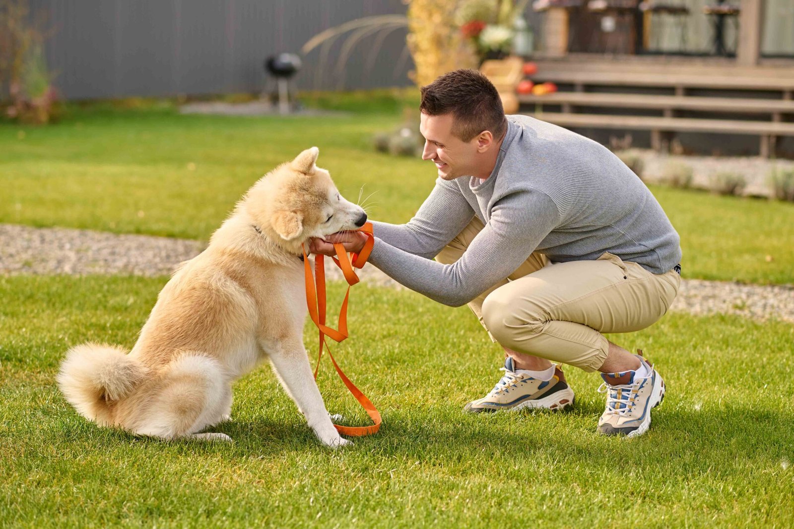 smart-dog-sideways-camera-joyful-young-adult-man-crouching-touching-friendly-smart-dog-with-leash-near-country-house-autumn-day